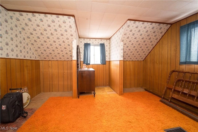 additional living space with wooden walls and light carpet