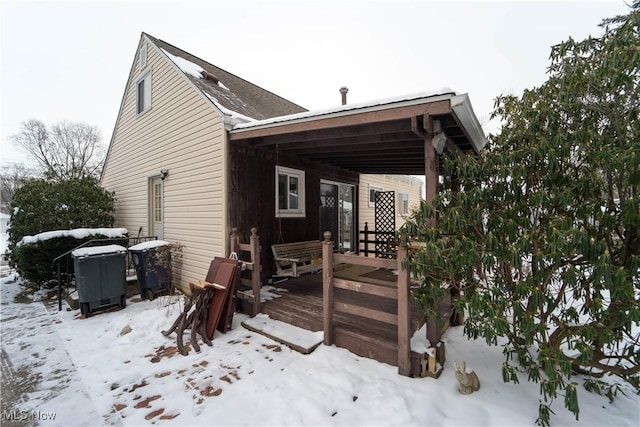 snow covered back of property featuring a wooden deck