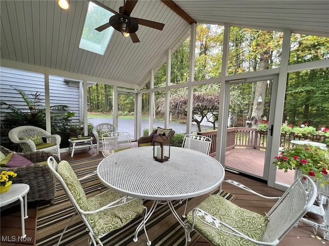 sunroom / solarium with a wealth of natural light, ceiling fan, and vaulted ceiling with skylight