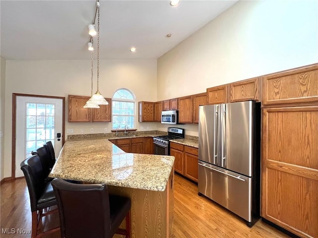 kitchen featuring pendant lighting, a kitchen bar, stainless steel appliances, and light hardwood / wood-style flooring