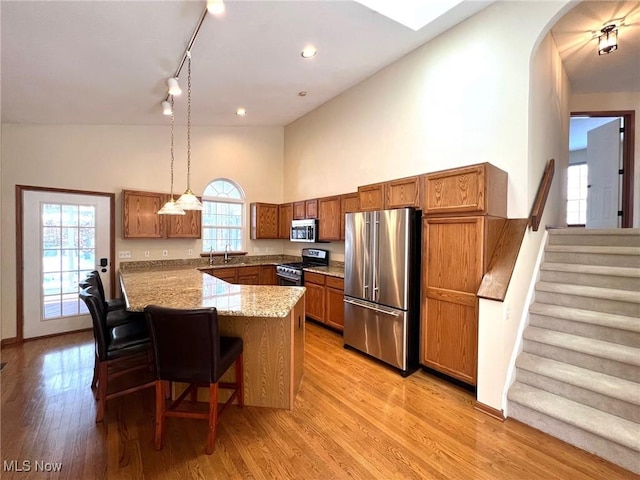 kitchen featuring a breakfast bar, decorative light fixtures, stainless steel appliances, and a wealth of natural light