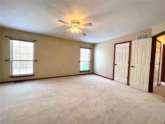 unfurnished room featuring light colored carpet, plenty of natural light, and ceiling fan