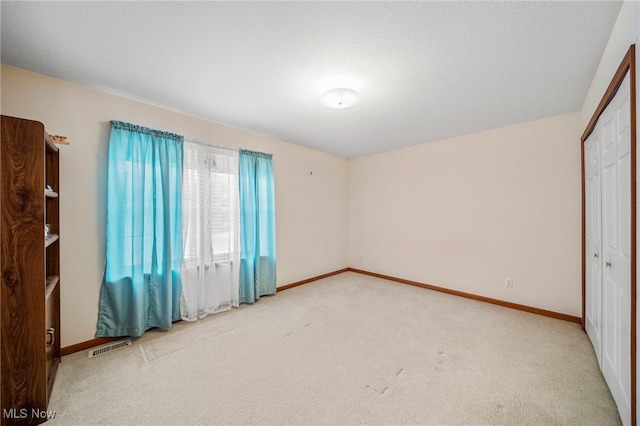 unfurnished bedroom featuring light carpet and a closet