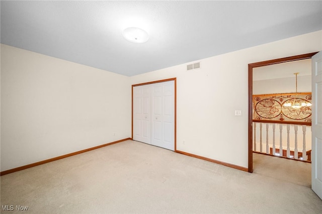 unfurnished bedroom with light carpet, a notable chandelier, and a closet