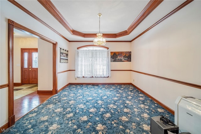 empty room featuring ornamental molding, carpet flooring, and a tray ceiling