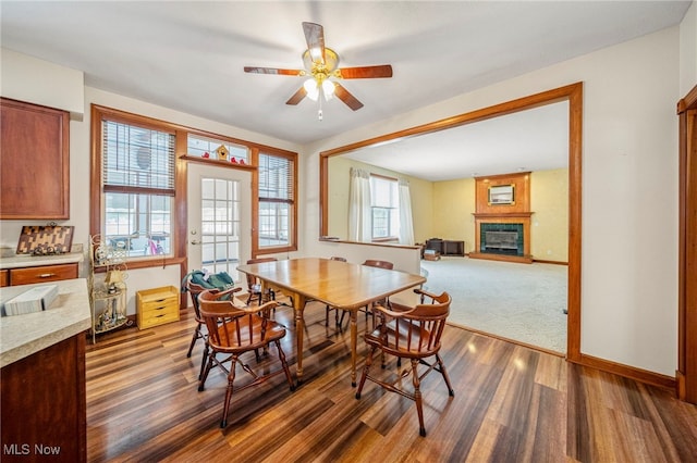 dining area with dark hardwood / wood-style flooring, a large fireplace, and ceiling fan