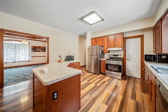 kitchen with light hardwood / wood-style floors, sink, hanging light fixtures, and black appliances