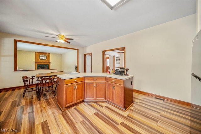 kitchen with light hardwood / wood-style flooring, a large fireplace, and ceiling fan