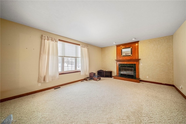 unfurnished living room featuring a tiled fireplace and carpet flooring