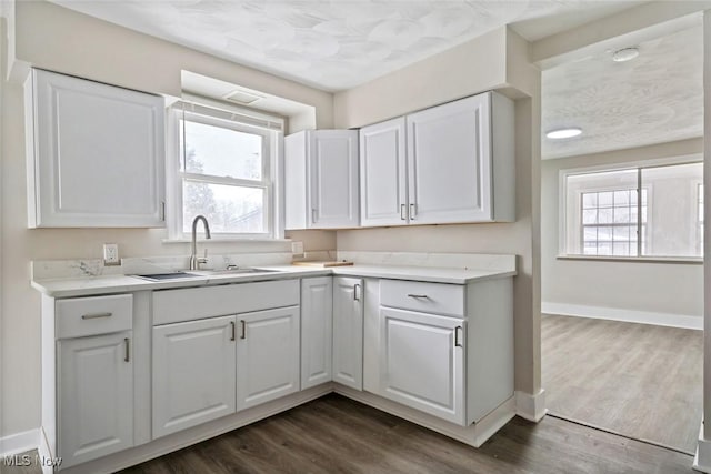 kitchen featuring a healthy amount of sunlight, white cabinetry, sink, and dark wood-type flooring