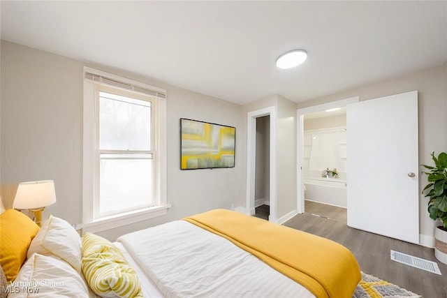 bedroom with ensuite bathroom and dark hardwood / wood-style flooring