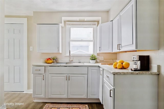 kitchen with white cabinetry, sink, and hardwood / wood-style flooring