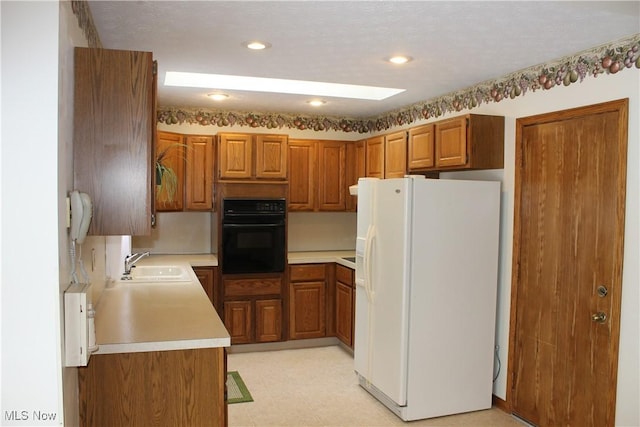 kitchen featuring oven, white fridge with ice dispenser, and sink