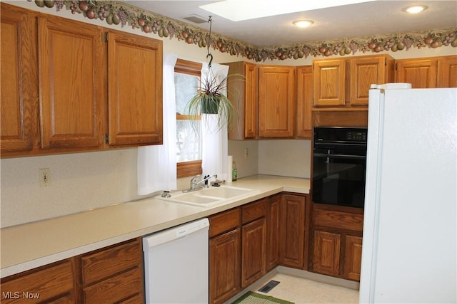 kitchen with a skylight, sink, and white appliances