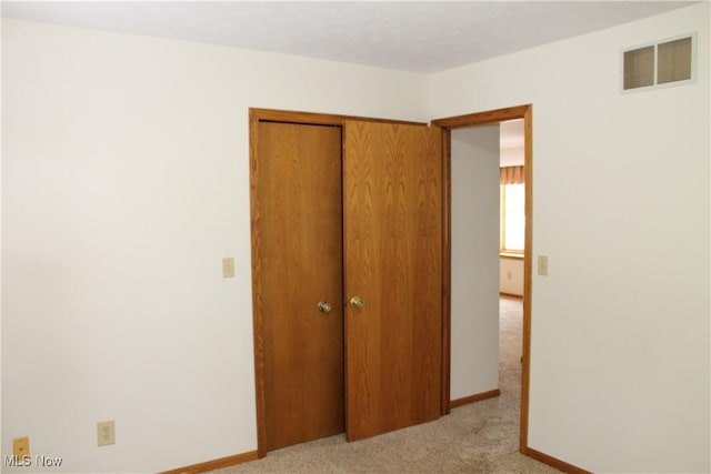 unfurnished bedroom featuring light carpet and a closet