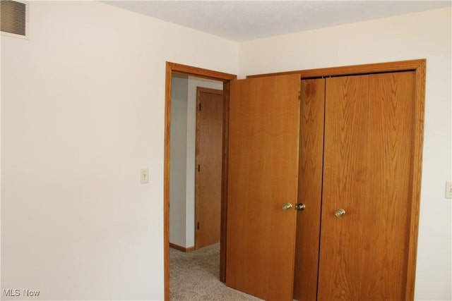 unfurnished bedroom featuring light carpet and a closet