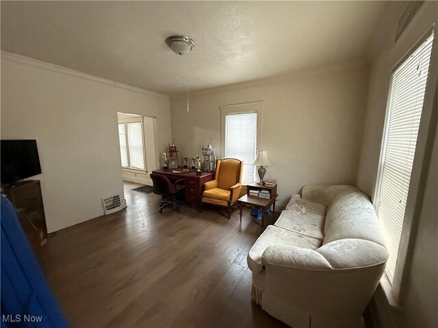 living area with ornamental molding and dark wood-type flooring