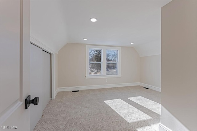 bonus room with light colored carpet and vaulted ceiling