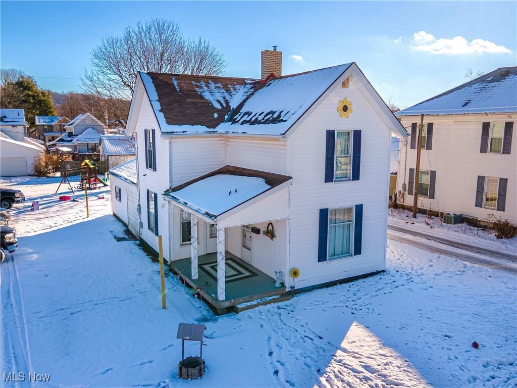 snow covered back of property featuring central AC