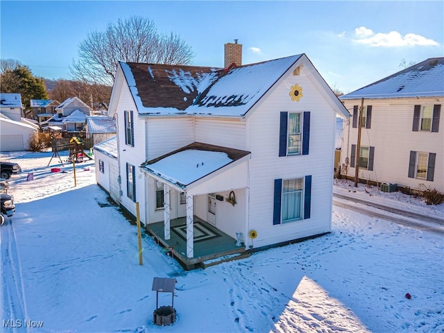 snow covered back of property featuring central AC