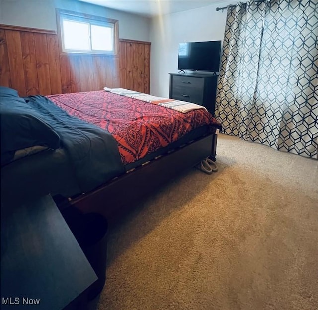 carpeted bedroom featuring wooden walls