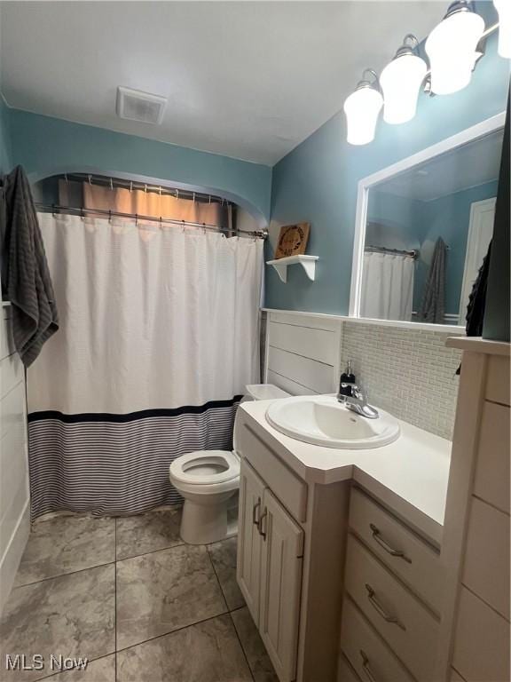 bathroom with vanity, toilet, and backsplash