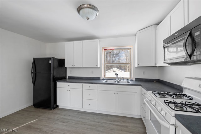 kitchen with white cabinetry, sink, black appliances, and light hardwood / wood-style flooring