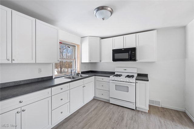 kitchen with light wood-type flooring, white cabinetry, white gas stove, and sink