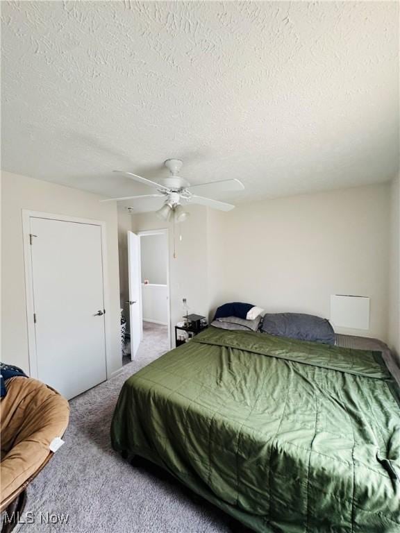 carpeted bedroom featuring a textured ceiling and ceiling fan