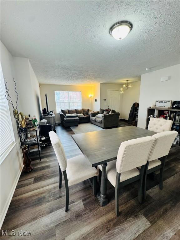 dining room featuring a notable chandelier, dark hardwood / wood-style floors, and a textured ceiling