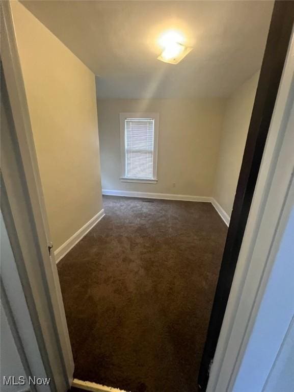 spare room with dark carpet