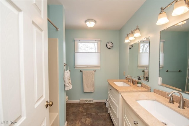 full bath with two vanities, baseboards, visible vents, and a sink