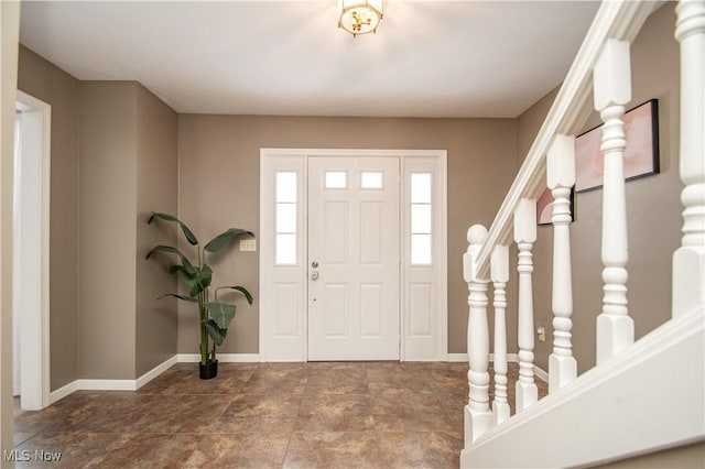 foyer featuring baseboards and stairs