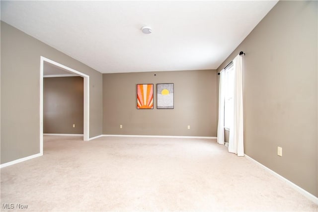 empty room featuring light colored carpet and baseboards