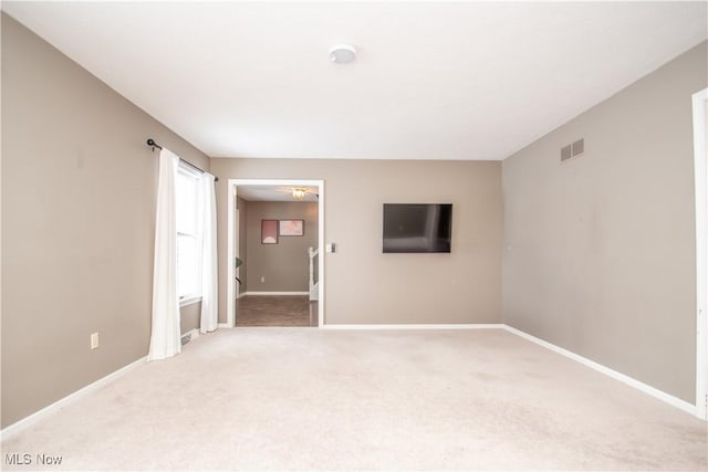 unfurnished room featuring light carpet, visible vents, and baseboards