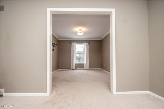 spare room with visible vents, light colored carpet, baseboards, and ornamental molding