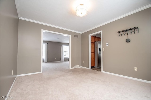 carpeted empty room with visible vents, baseboards, and ornamental molding