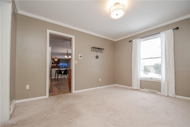 unfurnished room with visible vents, light colored carpet, crown molding, and baseboards