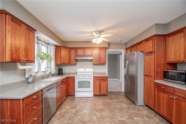 kitchen featuring a ceiling fan, a sink, under cabinet range hood, stainless steel appliances, and brown cabinetry