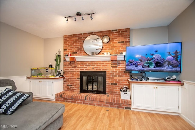 living area with a brick fireplace and wood finished floors