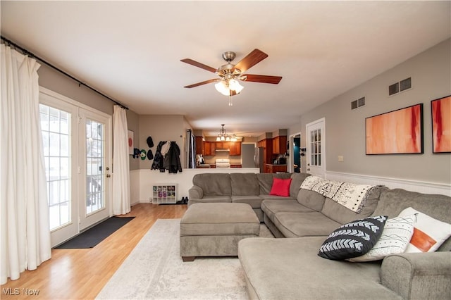 living area featuring visible vents, ceiling fan with notable chandelier, french doors, and light wood-style floors