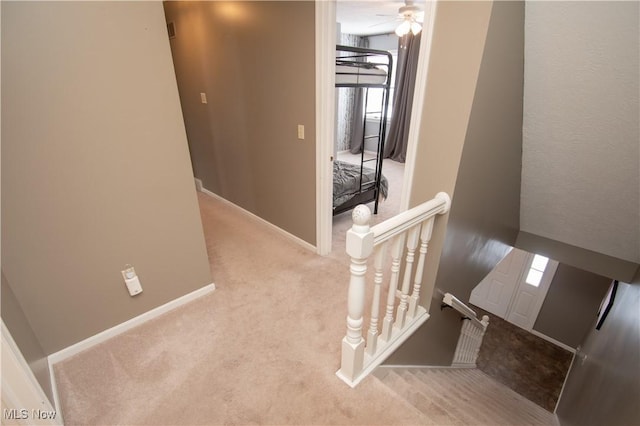 stairway with ceiling fan, baseboards, and carpet floors