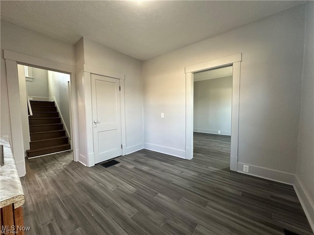 empty room with a textured ceiling and dark hardwood / wood-style flooring