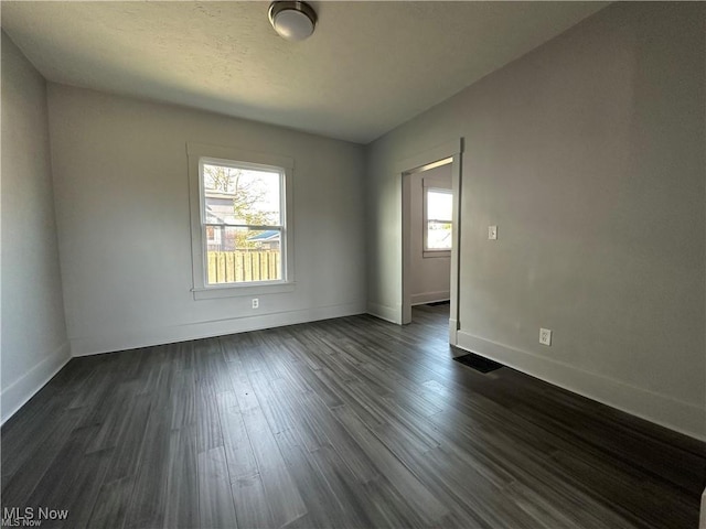 unfurnished room featuring dark wood-type flooring and a wealth of natural light