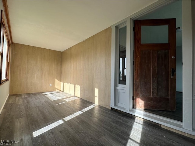 empty room featuring dark hardwood / wood-style flooring and wooden walls