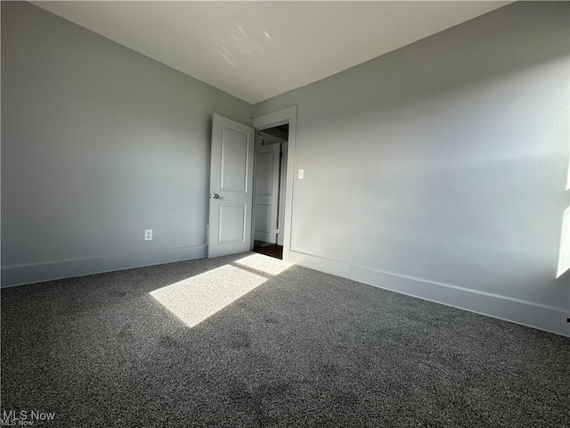 unfurnished room with dark colored carpet