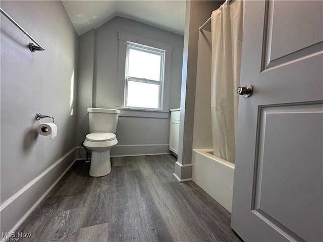 bathroom with toilet, hardwood / wood-style flooring, vaulted ceiling, and shower / bathtub combination with curtain