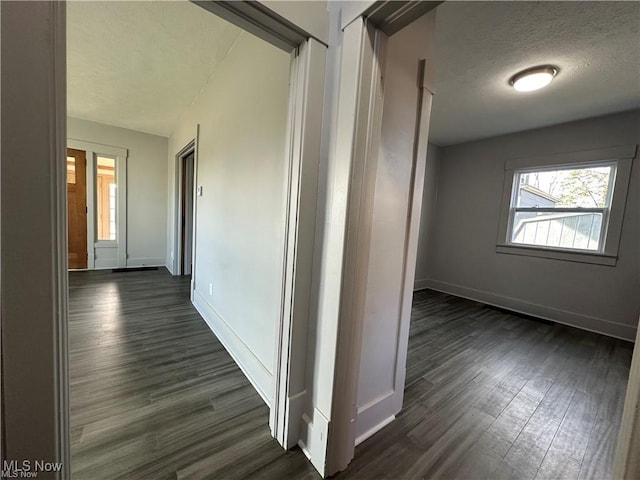 hall with dark wood-type flooring and a textured ceiling