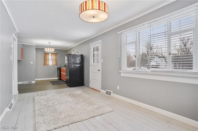 interior space with black refrigerator, wood-type flooring, pendant lighting, and crown molding