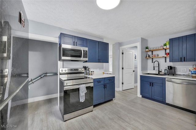 kitchen with stainless steel appliances, blue cabinets, light hardwood / wood-style floors, and sink